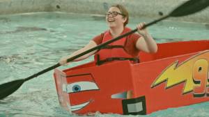 High school student participates in boat race competition using a corrugated cardboard boat