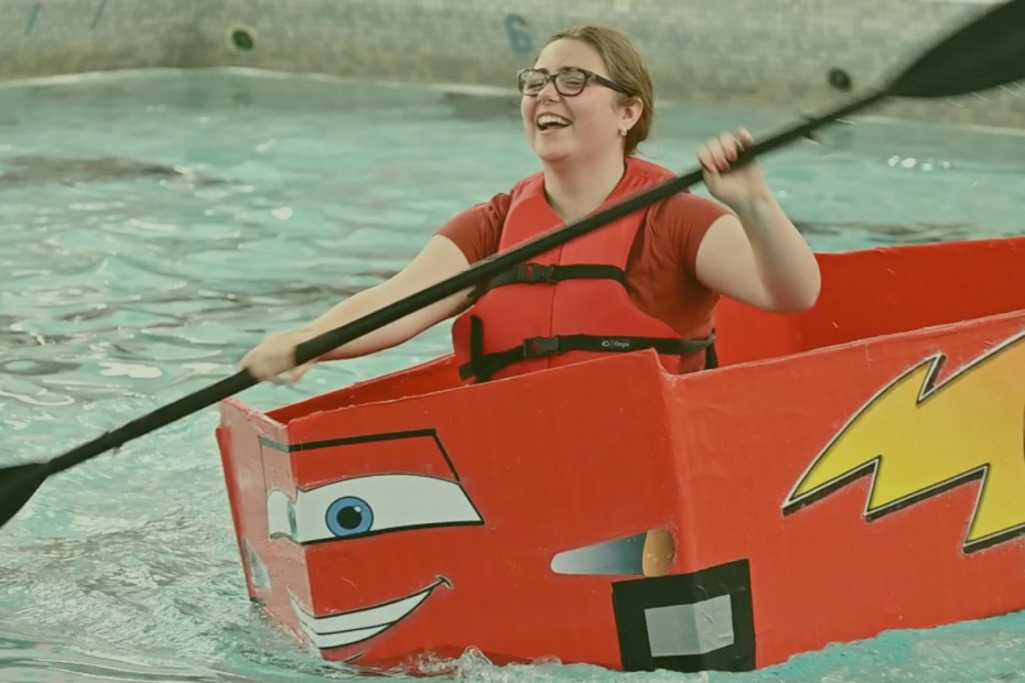 High school student participates in boat race competition using a corrugated cardboard boat
